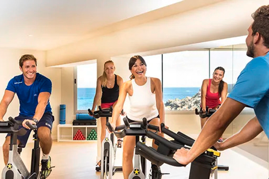 Eine Gruppe junger Menschen trainiert auf einem Spinning Fahrrad